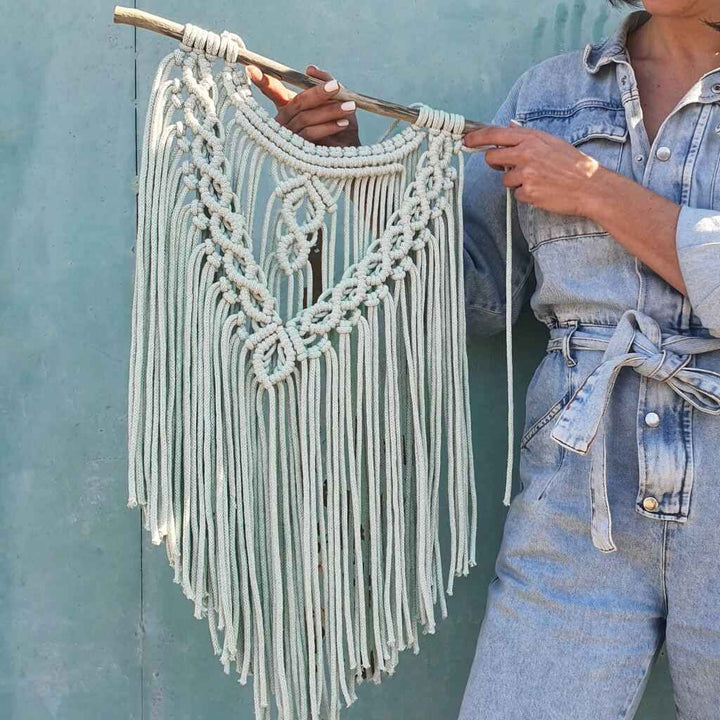 Frau hält Makramee-Wanddeko aus Bobbiny Premium Kordel in Milky Green.